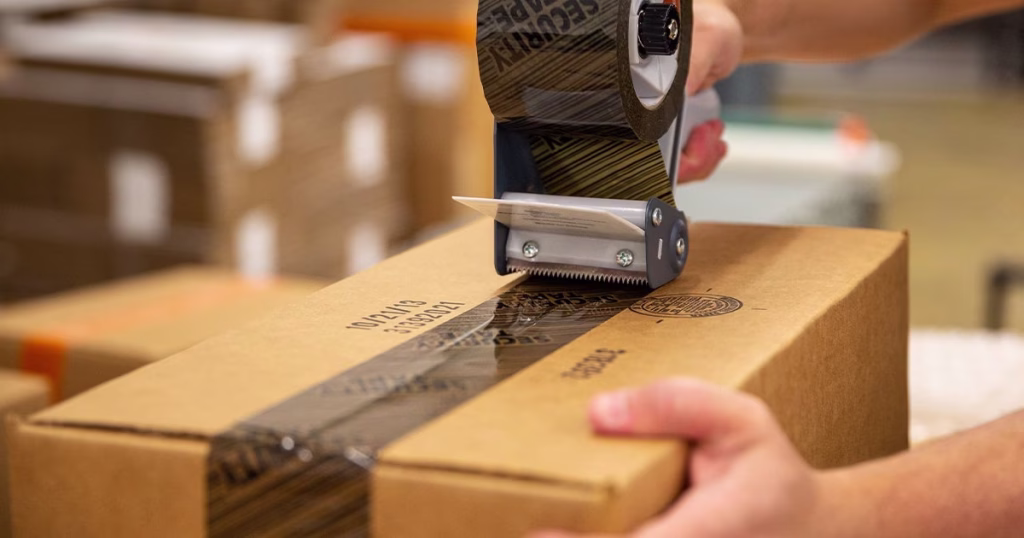 Security tape being applied to box with handheld dispenser